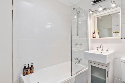 Un baño blanco con lavabo y ducha. en Scandi-chic Riverside Hideaway Near Attractions, en Hobart