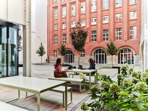 two women sitting at tables in a building at Basecamp by Xior Wrocław in Wrocław