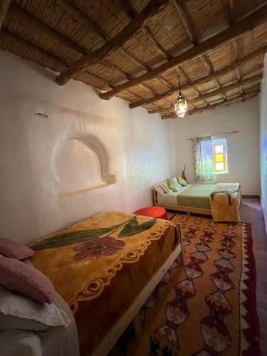 a bedroom with two beds and a rug at Auberge Bassou in Nkob