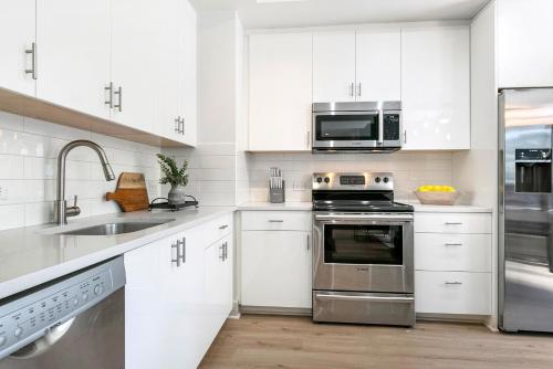 a kitchen with white cabinets and stainless steel appliances at Chic 4Bed Oasis Steps from French Quarter Magic! in New Orleans