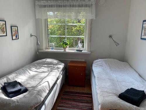 two twin beds in a room with a window at Sjökaptensgården Bed & Breakfast in Åsljunga