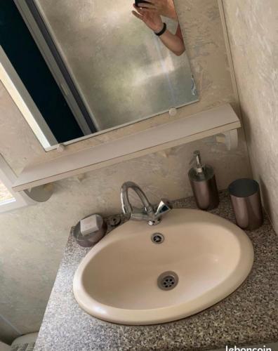 une personne prenant une photo d'un lavabo dans une salle de bains dans l'établissement Mobil home, à Castillonnès