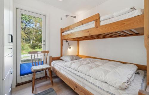 3 Bedroom Cozy Home In Aakirkeby في Vester Sømarken: غرفة نوم مع سرير بطابقين وكرسي ونافذة