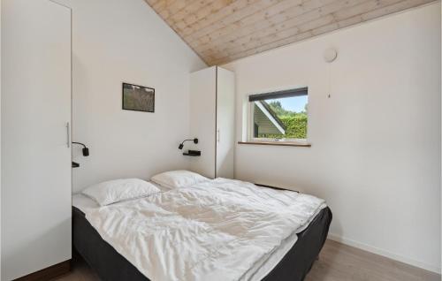 Cozy Home In Toftlund With Kitchen في Arrild: غرفة نوم بسرير بجدران بيضاء ونافذة