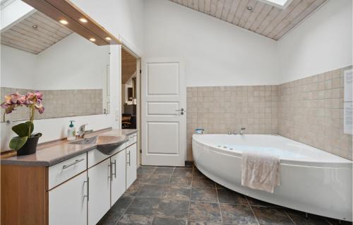 a bathroom with a large white tub and a sink at Cozy Home In Toftlund With Kitchen in Arrild