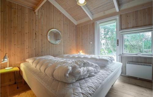 KnebelにあるAwesome Home In Knebel With 3 Bedrooms, Sauna And Wifiの木製の壁の客室の大型ベッド1台