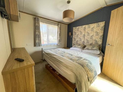 ein Schlafzimmer mit einem großen Bett und einem Holztisch in der Unterkunft Beautiful Caravan With Decking At Carlton Meres Holiday Park, Suffolk Ref 60001m in Saxmundham