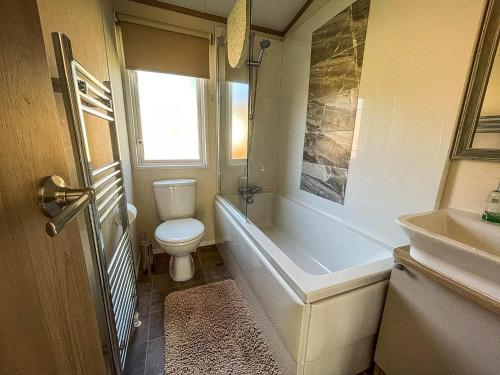 een badkamer met een toilet, een bad en een wastafel bij Beautiful Caravan With Decking At Carlton Meres Holiday Park, Suffolk Ref 60001m in Saxmundham