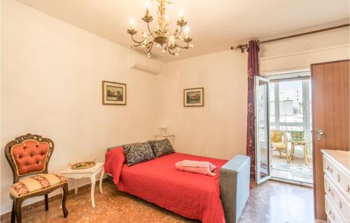 um quarto com uma cama vermelha e um lustre em 3 Bedroom Cozy Home In Chiaramonte Gulfi em Chiaramonte Gulfi
