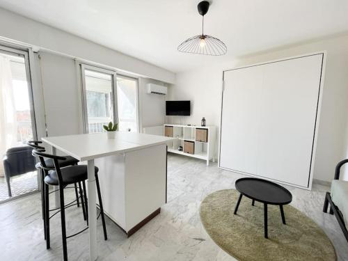 une cuisine blanche avec une table et des chaises dans une pièce dans l'établissement Le guynemer, à Beausoleil