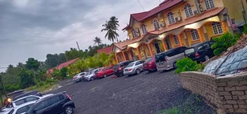 een rij auto's geparkeerd voor een gebouw bij RAZ HOTEL PANTAI PERANGINAN KELULUT in Marang