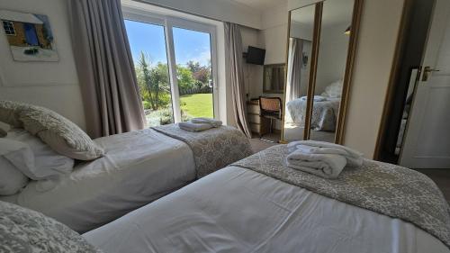 two beds in a room with a large window at Heathfield in Saint Mawes