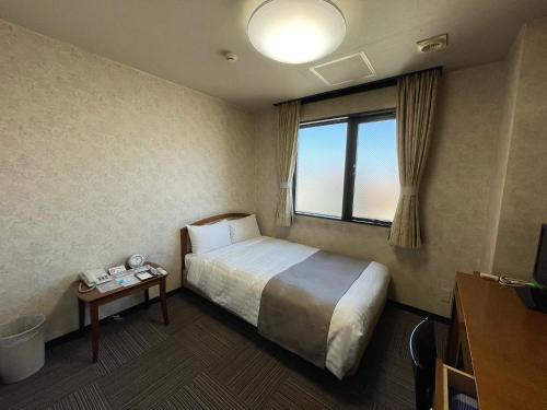 a hotel room with a bed and a window at UrbanHotelTokyoShinmatsudo in Matsudo