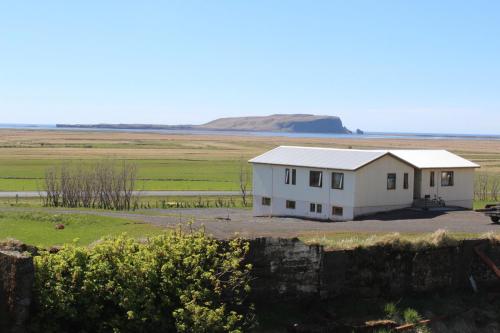 a white house in the middle of a field at Skammidalur Guesthouse in Vík