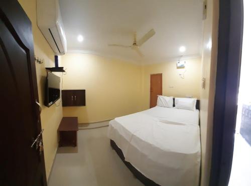 a hotel room with a white bed and a television at MSN Residency in Srikalahasti