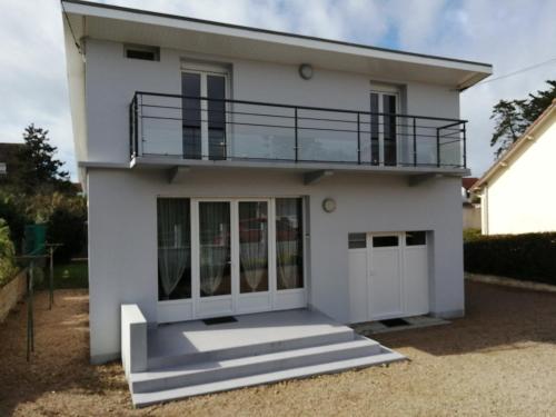 Una casa blanca con un balcón encima. en Au Bon ENdrOIT, en Barneville-Carteret