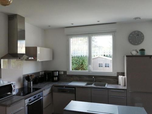 une cuisine avec un évier et une fenêtre dans l'établissement Au Bon ENdrOIT, à Barneville-Carteret