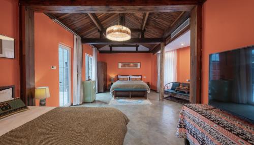 a bedroom with orange walls and two beds and a television at Beijing Unified Courtyard Hotel in Beijing