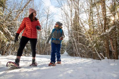 a woman and a child on skis in the snow at Lake Placid Inn Boutique Hotel in Lake Placid