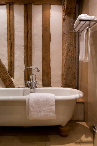 La salle de bains est pourvue d'une baignoire blanche et de murs en bois. dans l'établissement Golf de Rebetz- Domaine de Rebetz, à Chaumont-en-Vexin