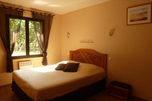 Schlafzimmer mit einem großen Bett und einem Fenster in der Unterkunft Gite en forêt landaise avec jacuzzi d'intérieur in Pissos
