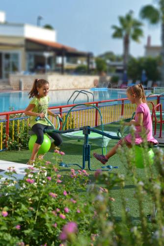 two little girls sitting on a bench at a park at Aegean Houses in Kos Town