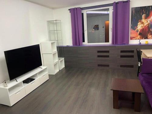 a living room with a flat screen tv and purple curtains at Janis poils home 1 in Ventspils
