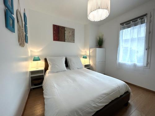 a white bedroom with a large bed and two night stands at EDEN By Dream Apartments in Chessy