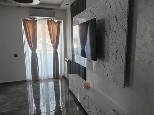 a living room with a television on a wall at Hedonic Wellness Apartmani in Niš