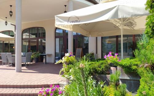 a patio with an umbrella and flowers in front of a building at Restauracja Kargul noclegi in Łęczyca