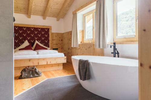 a bathroom with a large tub and a bed at Feelfree Nature Resort in Oetz