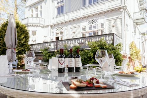 - une table en verre avec des bouteilles de vin et des assiettes de nourriture dans l'établissement Roze Boutique Hotel, à Liepāja