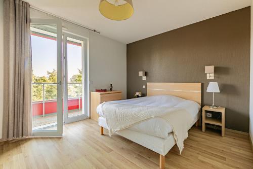 a bedroom with a bed and a large window at OVELIA Strasbourg - Les Jardins des Deux Rives in Strasbourg