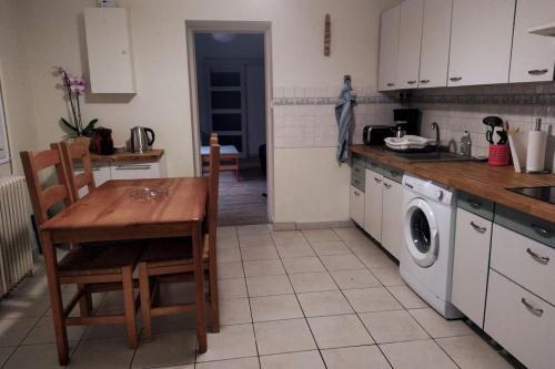 une cuisine avec une table et une machine à laver dans l'établissement maison agréable avec stationnement privatif, à Angoulême