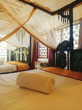 a bedroom with two beds and a large window at Lux Suites kivulini Cottages Diani Beach in Diani Beach