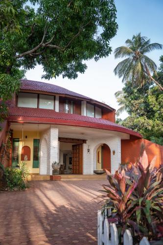 a house with a palm tree in front of it at LohonoStays Villa Lani in Alibag
