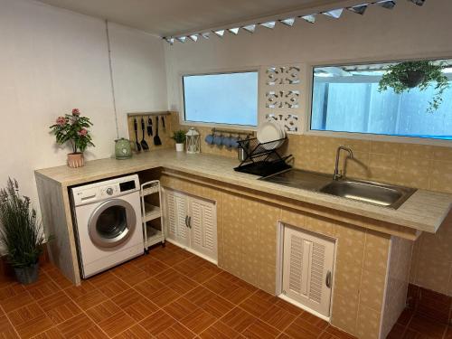 a kitchen with a sink and a washing machine at Bonneville Beach House in Thai Muang
