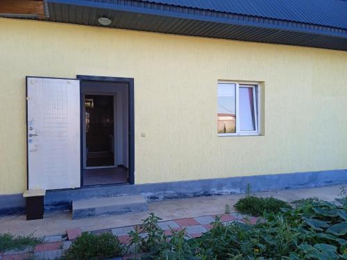 um edifício amarelo com uma porta e uma janela em Частый дом em Kapchagay