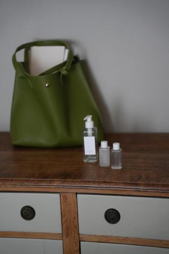 a green purse and a bottle of soap on a wooden table at iNkosi Luxury Lodge in Parow