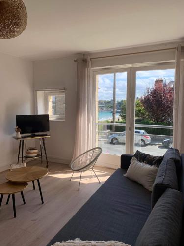 a living room with a blue couch and a large window at Appartement 40m2 vue sur mer accès direct plage et parking privé in Dinard