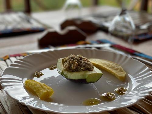 a white plate with an avocado with nuts and fruit at Monte Mar SãoTomé in M. Peixe