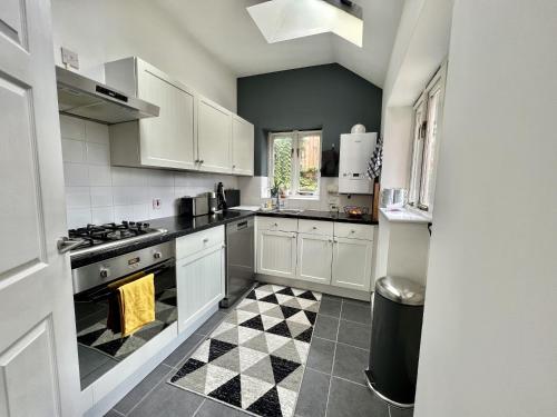 a kitchen with white cabinets and a checkered floor at Tailor That Property - High Street in Northampton