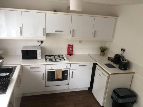 cocina blanca con fogones y microondas en Bluebell House 2 bedroom with parking and garden, en Scunthorpe