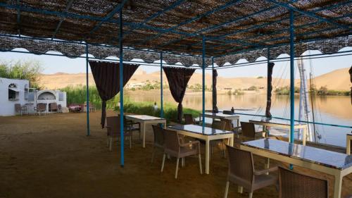 ein Restaurant mit Tischen und Stühlen und Flussblick in der Unterkunft Nile View (2) Guest House in Assuan