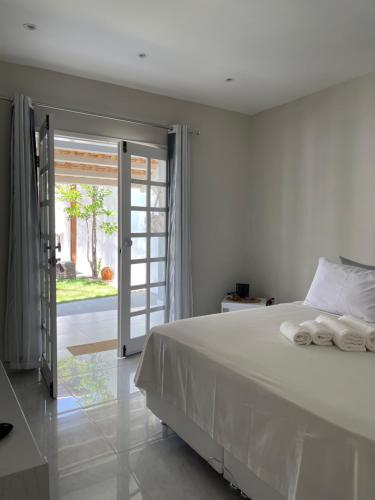 1 dormitorio con cama blanca y puerta corredera de cristal en Charlotte House en Canoa Quebrada