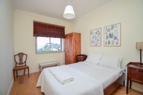 a bedroom with a white bed and a chair at Cozy apartment near the beach in Estoril