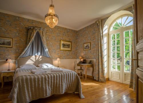 Schlafzimmer mit einem Bett, einem Fenster und einem Tisch in der Unterkunft L'Orangerie du Grand Jardin in Condé-sur-Seulles