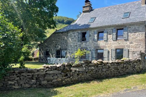 an old stone house with a stone wall at Gîte pour 9 personnes avec jardin à proximité du Puy Mary in Le Claux