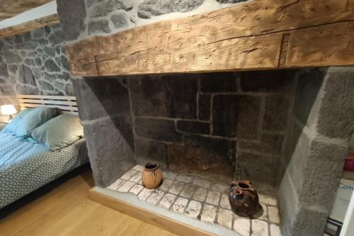 a stone fireplace with two vases sitting next to a bed at Gîte pour 9 personnes avec jardin à proximité du Puy Mary in Le Claux
