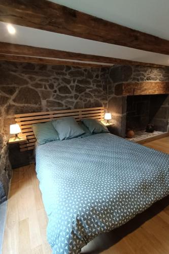 a bedroom with a bed with a stone wall at Gîte pour 9 personnes avec jardin à proximité du Puy Mary in Le Claux